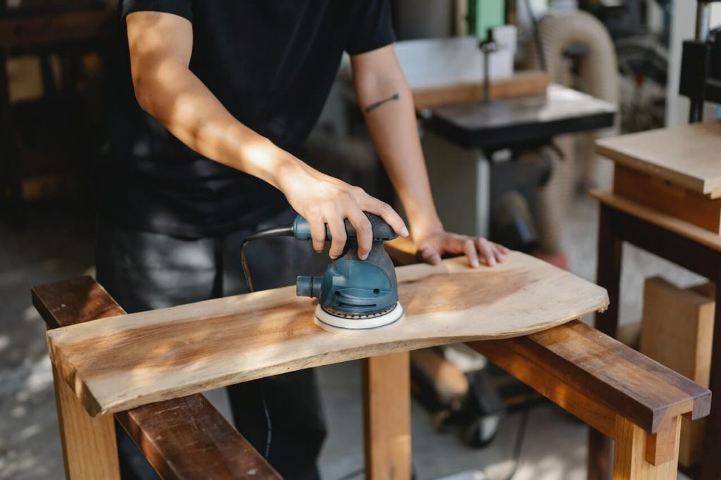 A person planing wood, using a hand plane to shape and smooth the surface of the wood.